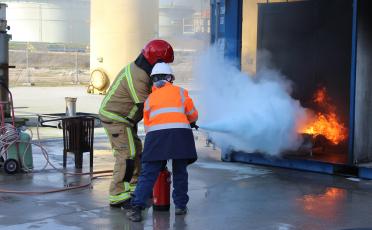 trainer firefighter assisted by his trainee on hydrocarbon fire and extinguishing it.